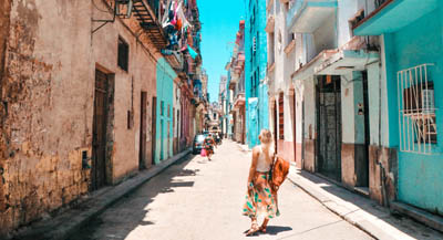 A traveller dragging luggage through mediterrenean looking street.